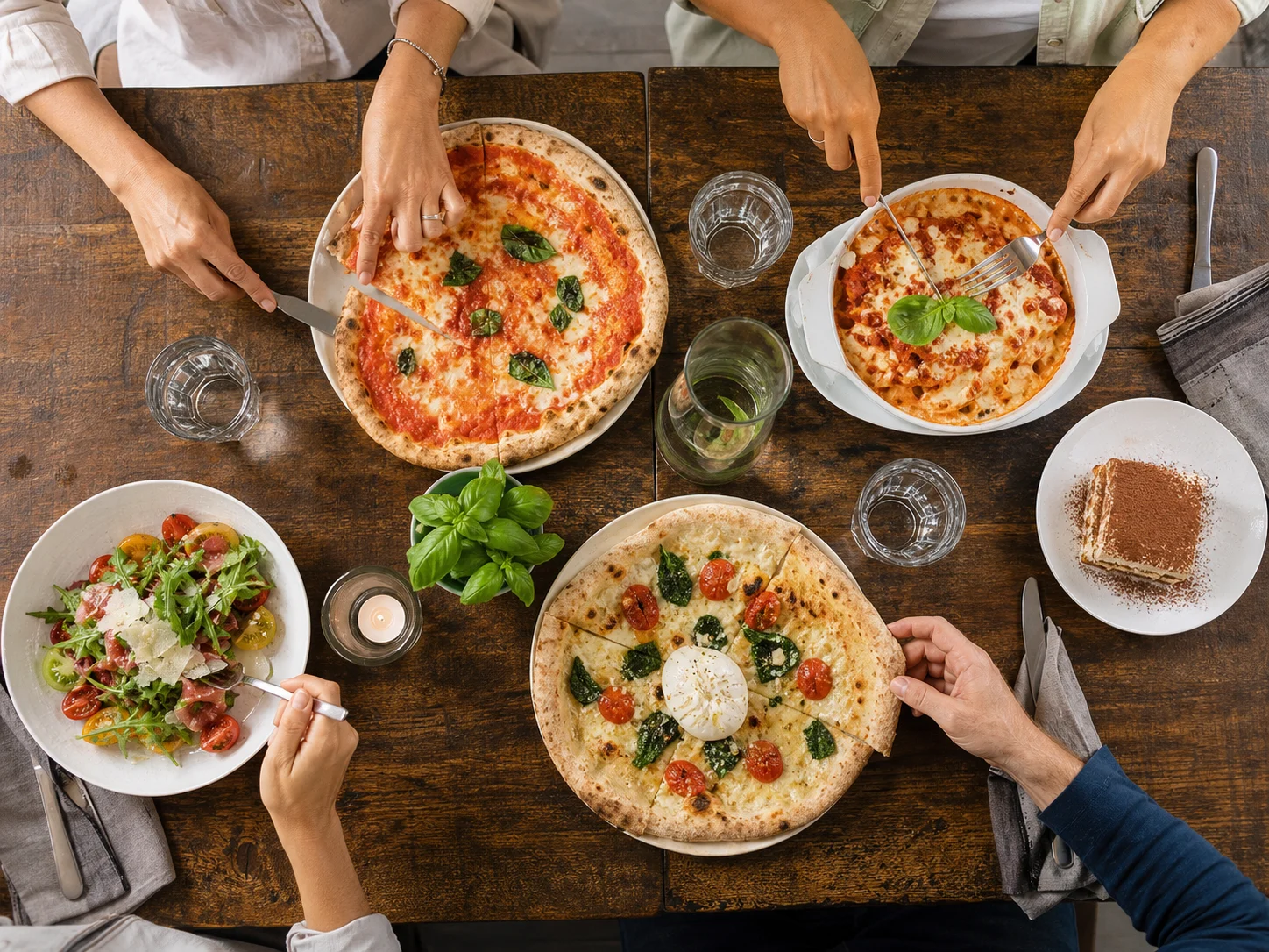 Gemeinsamer Tisch mit Pizza, Pasta, Salat und Tiramisù